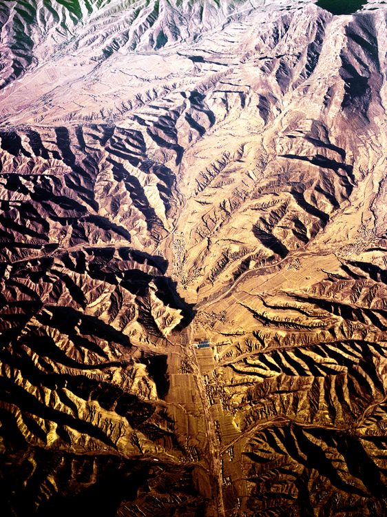 Luftbildaufnahme einer gebirgigen, zerfurchten Landschaft