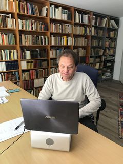 Hans-Ulrich Wagner am Laptop in einem Büro mit großem Bücherregal.