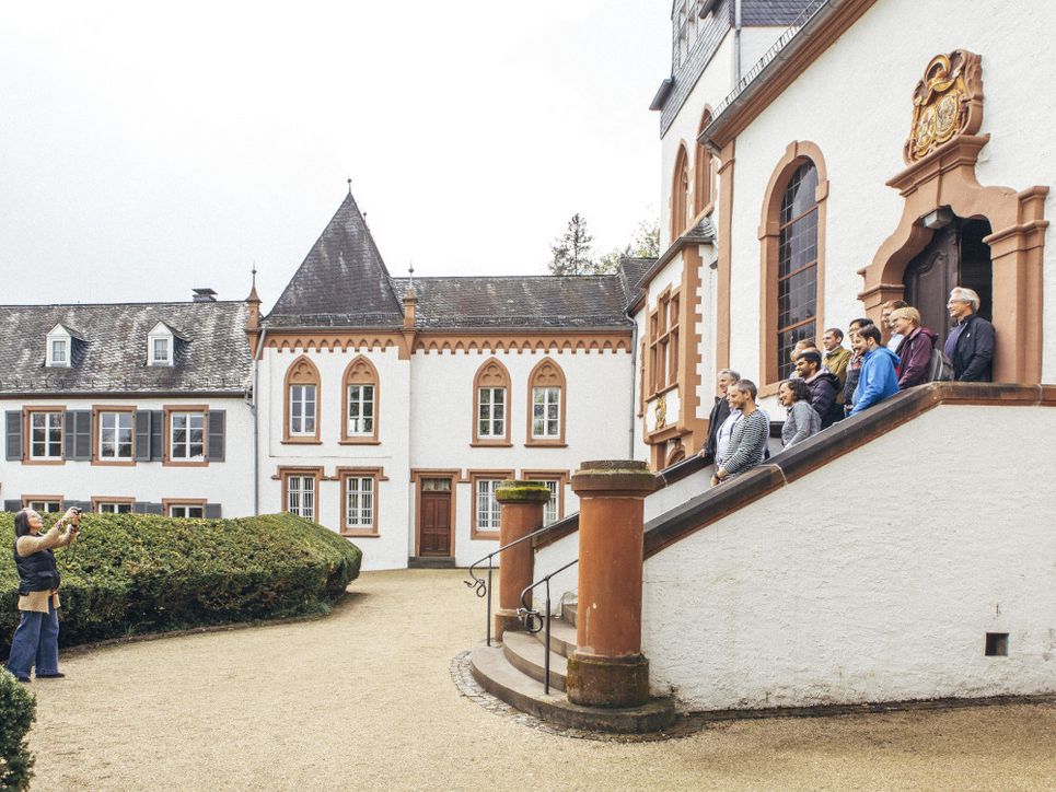 Fotografin macht ein Gruppenfoto von Personen, die auf einem Treppenaufgang auf Schloss Dagstuhl stehen.
