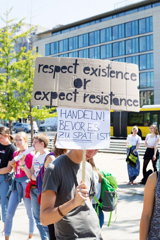 Schüler trägt ein Plakat mit der Aufschrift "respect existence or expect resistance" und "Handeln, bevor es zu spät ist".
