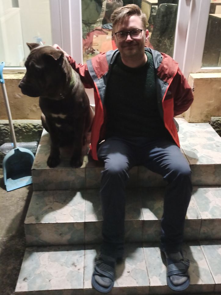 Nils Hein sitzt neben einem Hund auf einem Treppenabsatz.