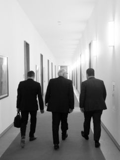 Wilhelm Bauer, Matthias Kleiner und Hubertus Klein gehen einen Flur entlang. Man sieht sie von hinten.