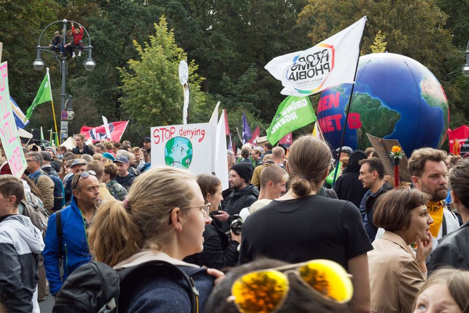 Klima-Demonstration mit Flaggen, Bannern und gebasteltem Globus.