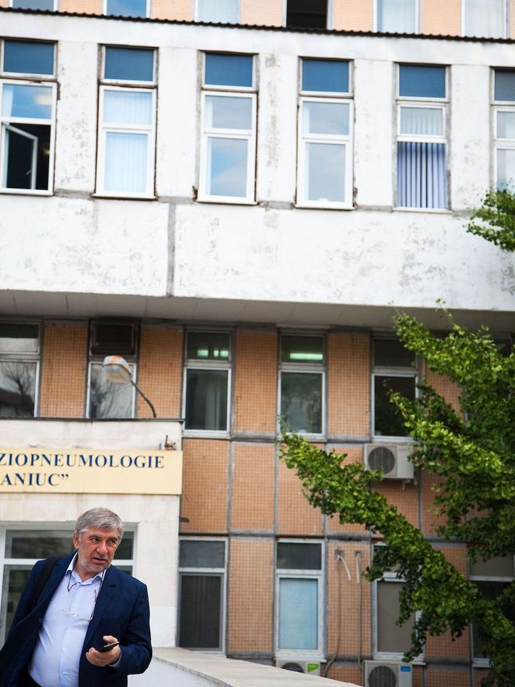 Valeriu Crudu mit Smartphone in der Hand vor einem mehrstöckigen Gebäude.