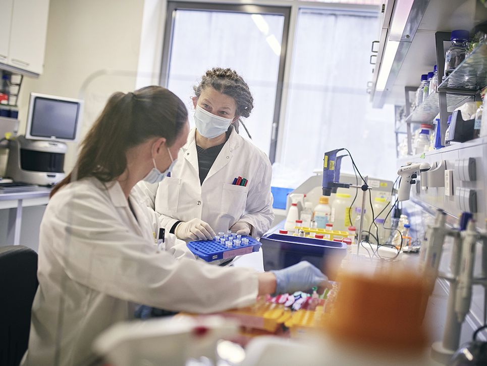 Ilse Jacobsen mit einer weiteren Wissenschaftlerin im Labor, sie hält ein Plastiktablett mit kleinen Proben in der Hand.