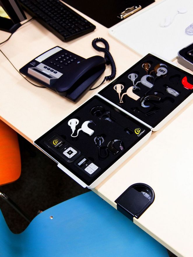 Schreibtisch mit einem Telefon und Implantaten in verschiedenen Farben.