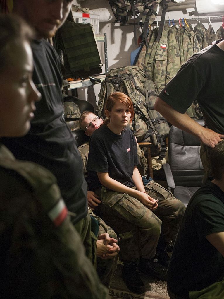 Jugendliche Mitglieder eines Schützenverbands in einem kleinen Raum mit Materialien und Uniformen.
