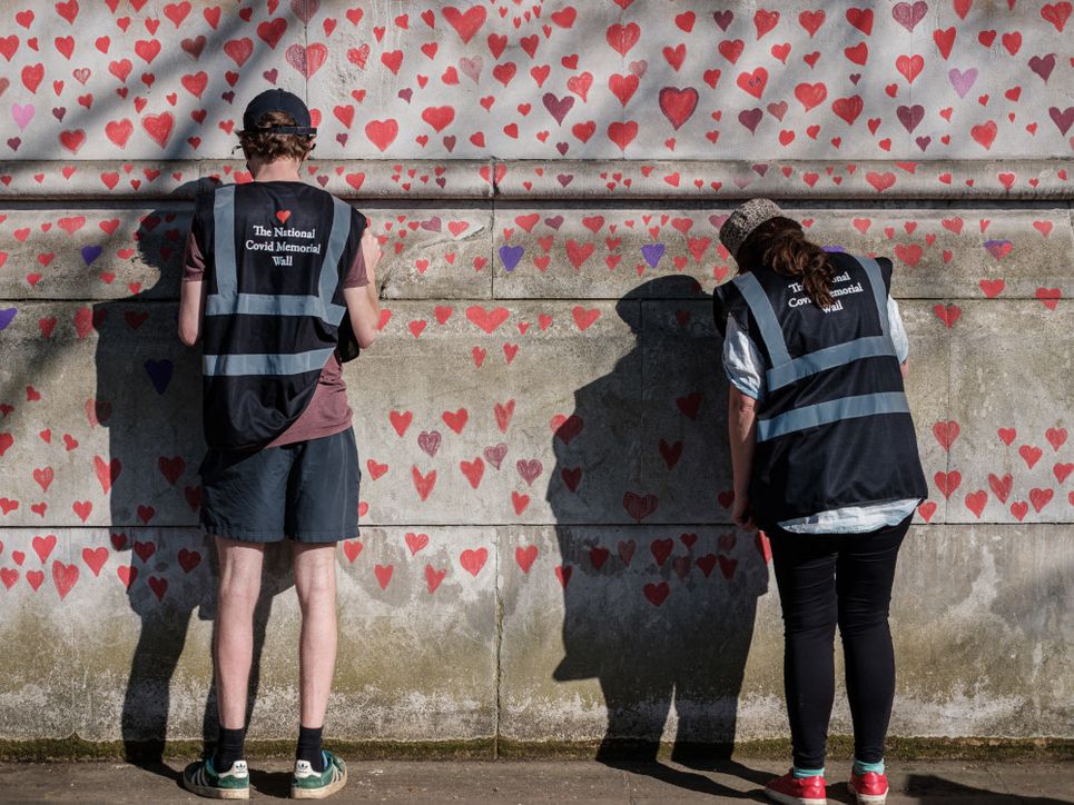 Zwei Personen malen Herzen auf eine Mauer.