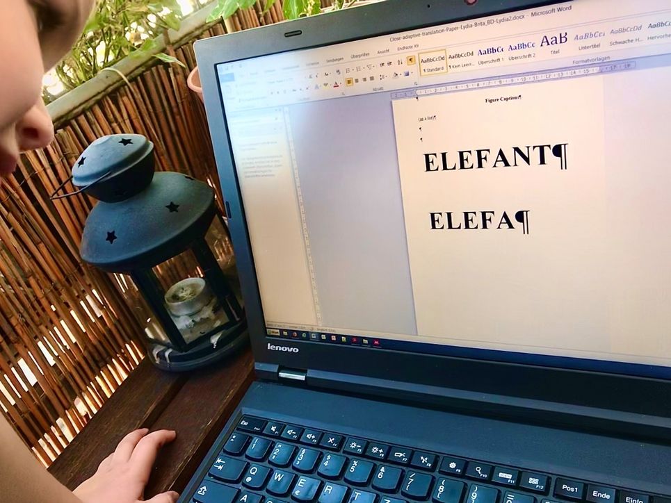 Ein Kind tippt Elefant in Großbuchstaben in ein Dokument auf dem Laptop.