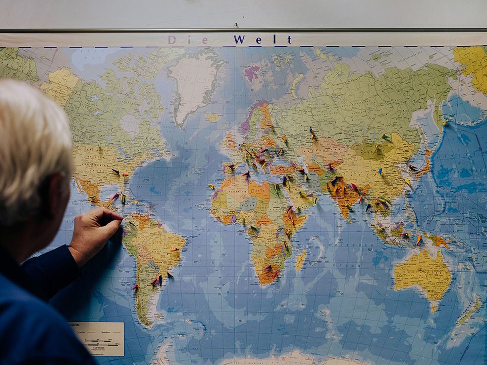 Ludger Wessjohann steckt Fähnchen auf eine Weltkarte.