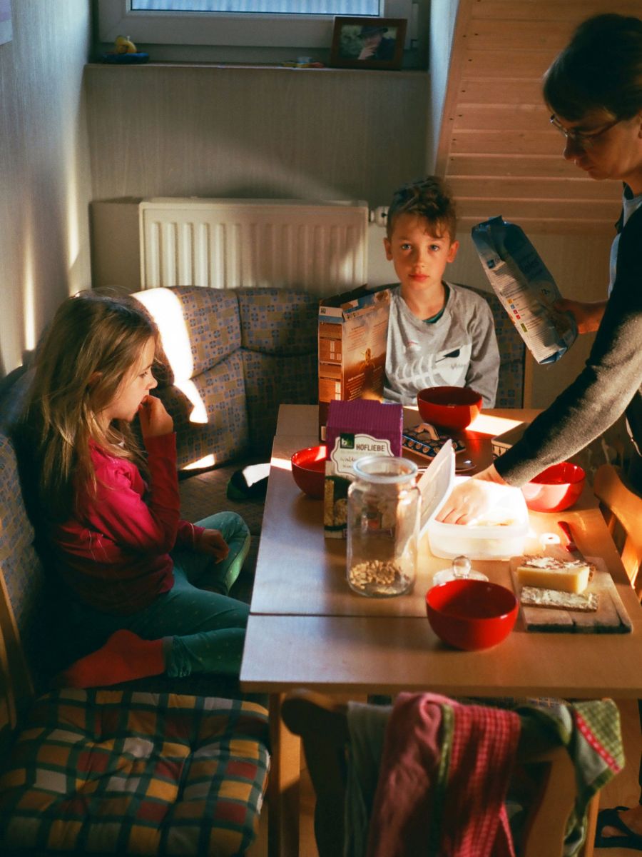 Zwei Kinder mit ihrer Mutter am Frühstückstisch.