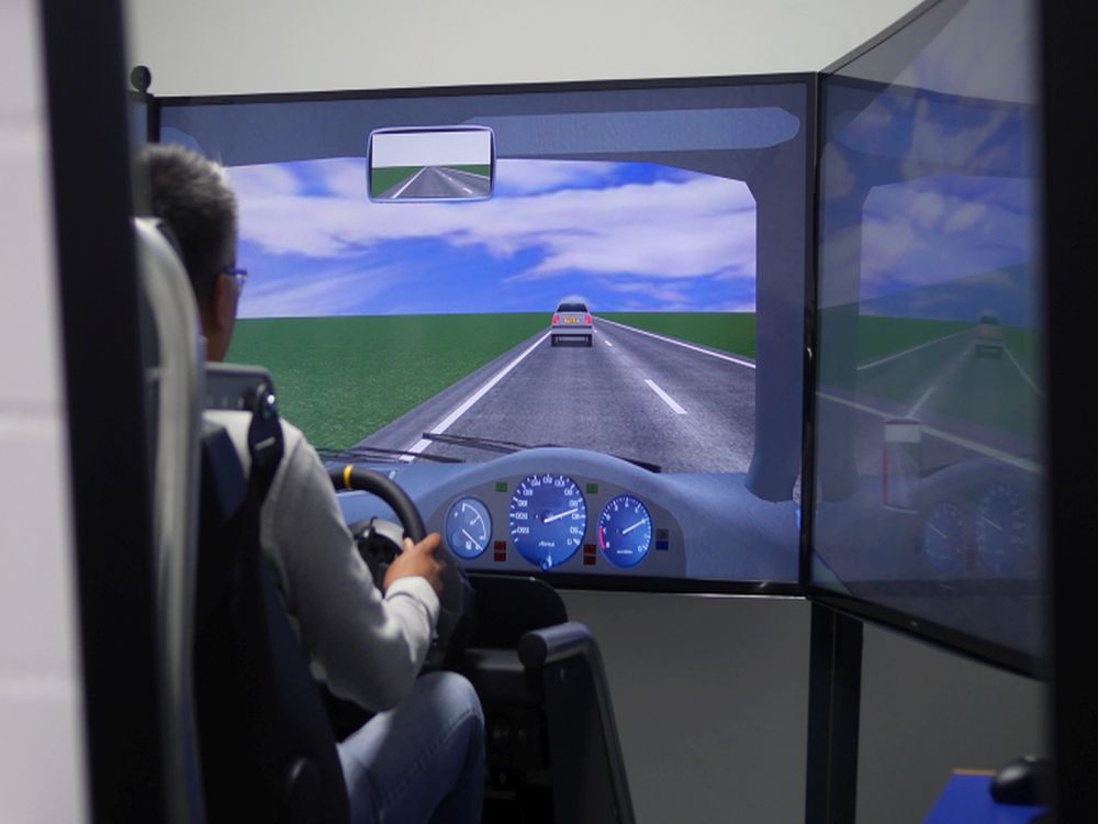 Eine Person im Fahrsimulator mit Blick auf eine virtuelle Landstraße.