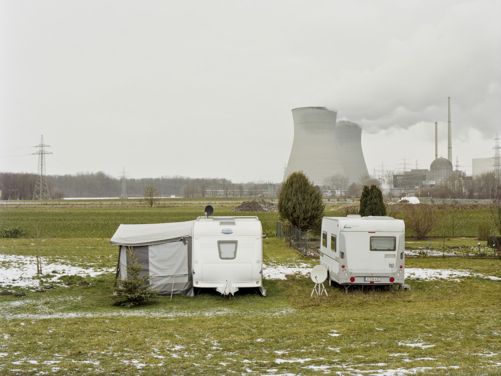Zwei Wohnwägen auf einer Wiese, im Hintergrund ein Atomkraftwerk.