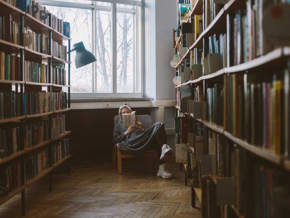 Lesende in einem Sessel in einer Bibliothek.